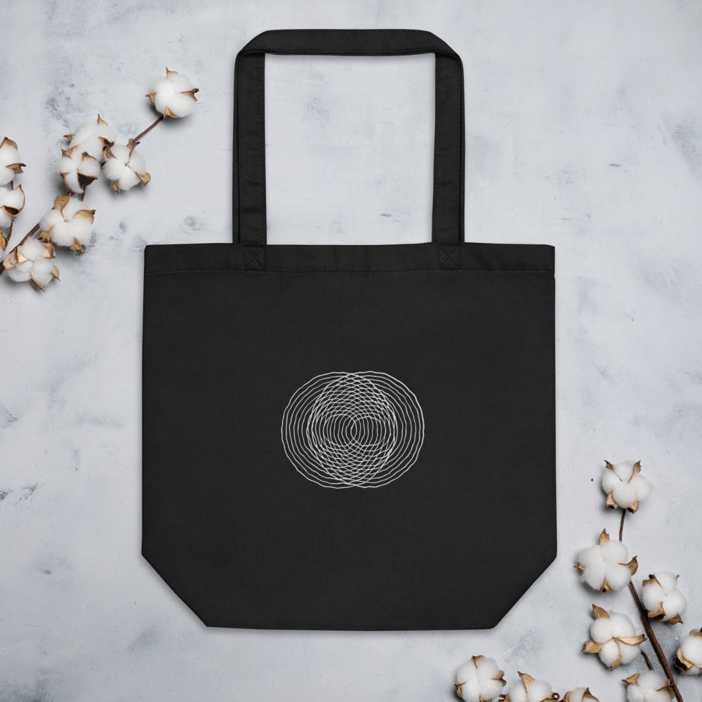 A minimalist diagram of intersecting concentric raindrop ripple rings printed on a tote bag. Flat lay, Ink colourway.
