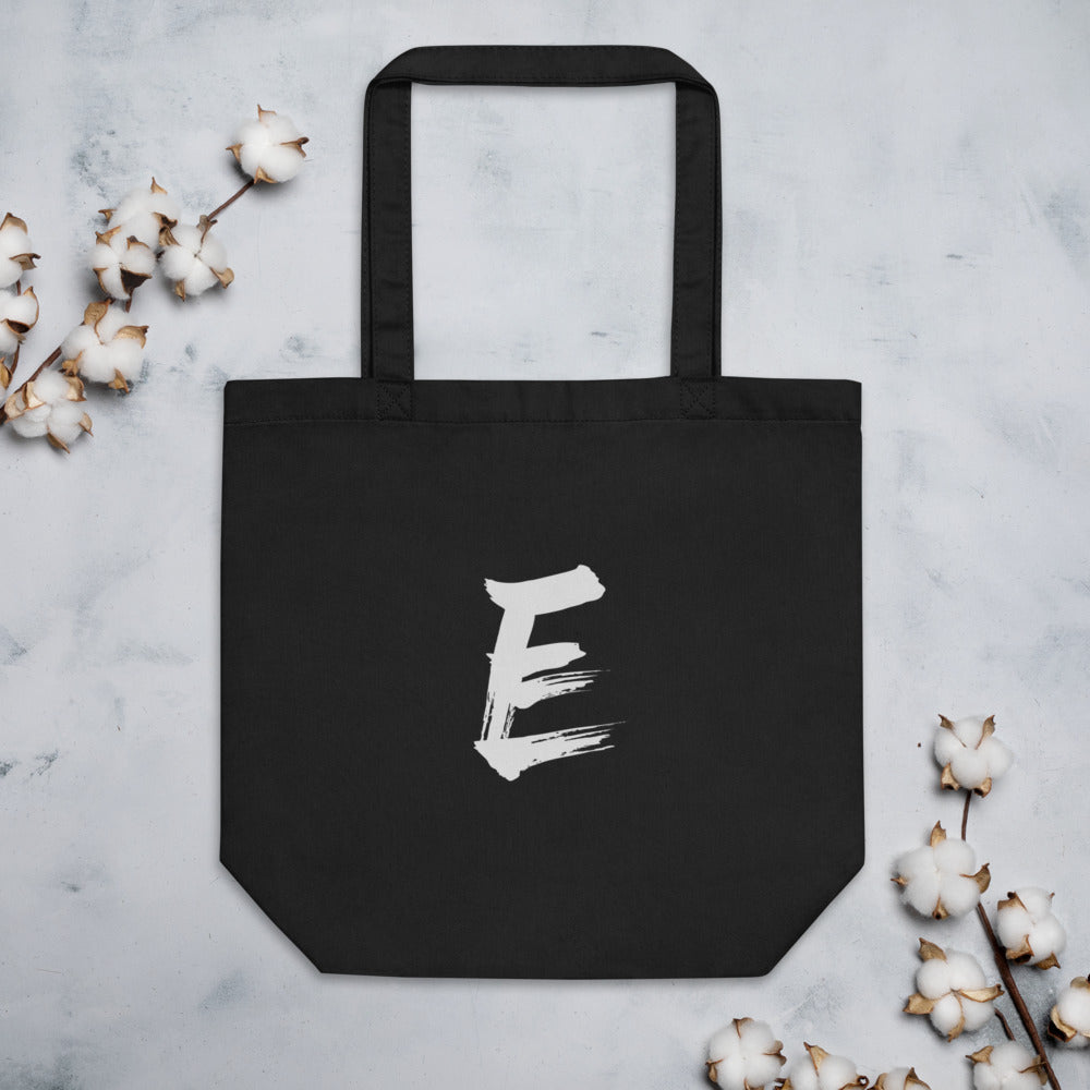 A minimalist sumi-e style capital letter E printed in black ink on a tote bag. Flat lay, Ink colourway.