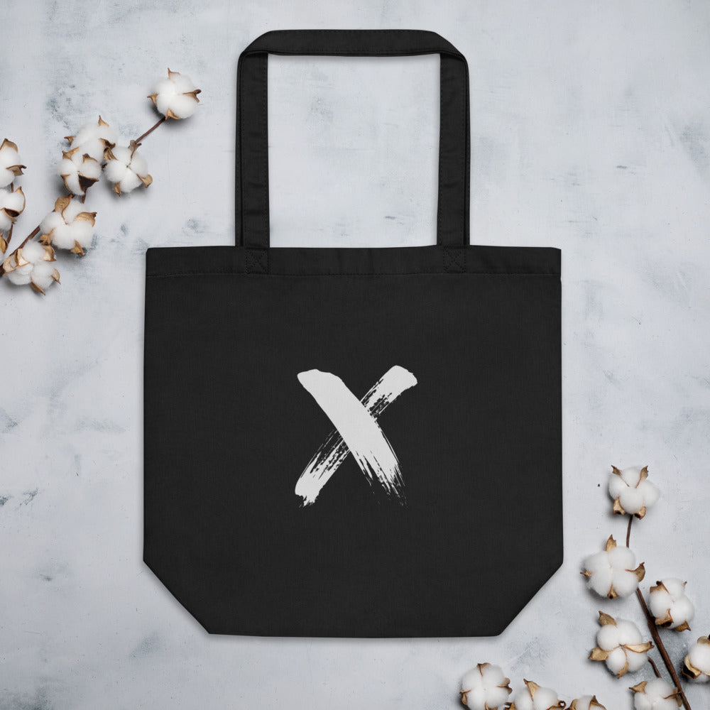 A black ink sumi-e calligraphy letter X printed on a canvas tote bag. Flat lay, Ink colourway.