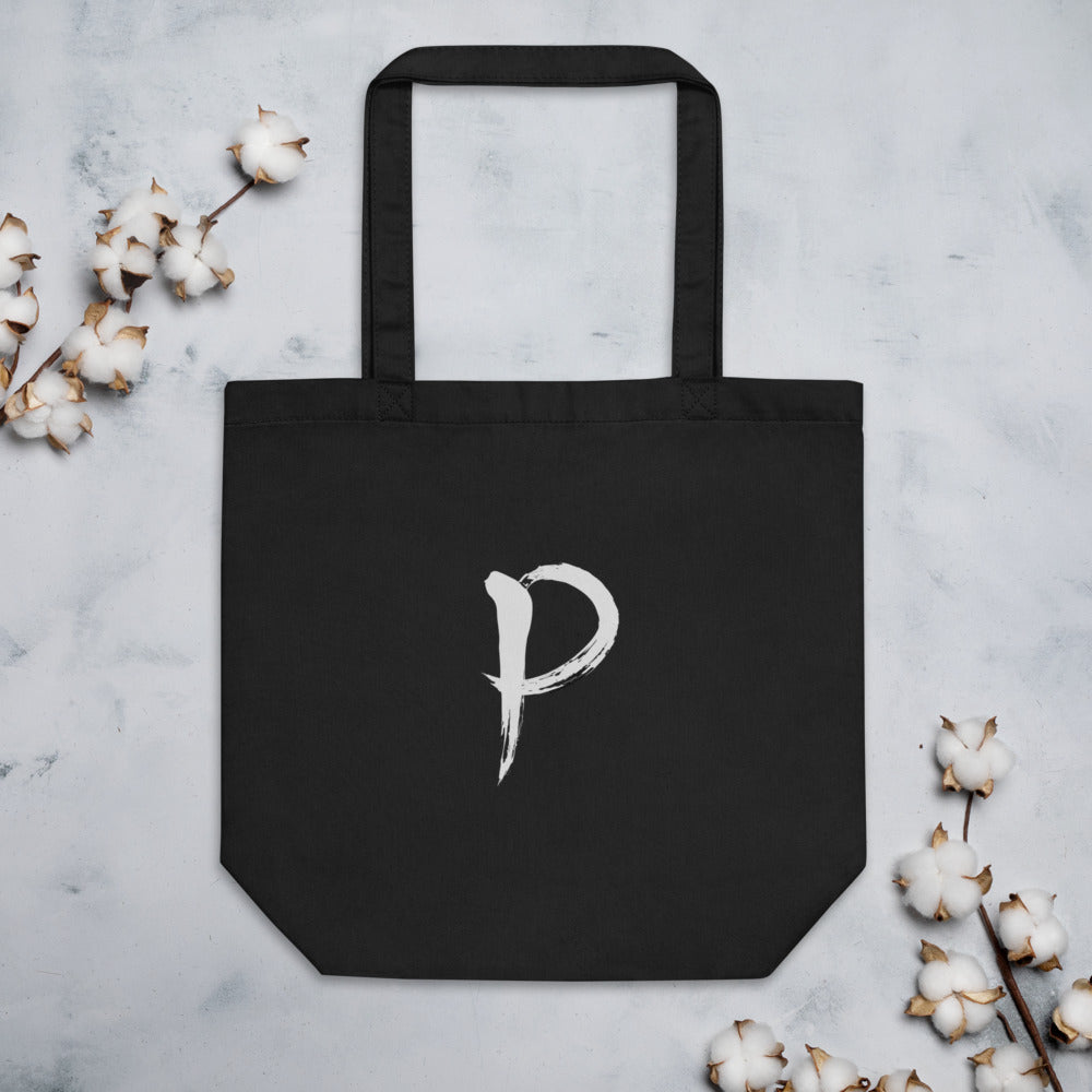 The letter P in black sumi-e brush calligraphy printed on a tote bag. Flat lay, Ink colourway.