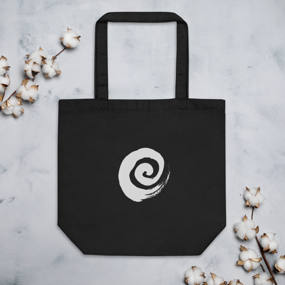 A minimal sumi-e spiral representing a coiled snail shell printed on a tote bag. Flat lay, Ink colourway.