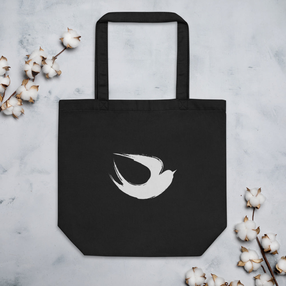 A minimalist sumi-e ink brush painting of a flying swallow on a tote bag. Flat lay, Ink colourway.
