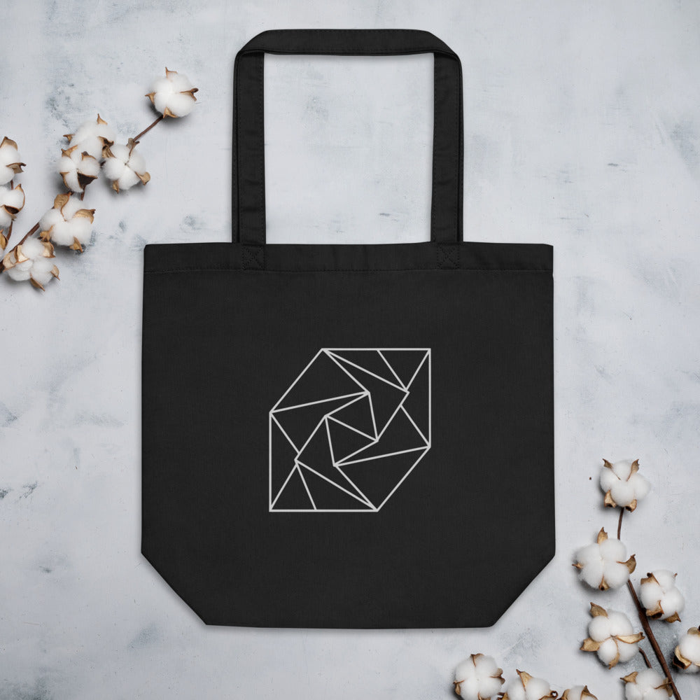 A spiral progression of twelve folded triangular planes in a hairline-weight line art print on a classic tote bag. Flat lay, Ink colourway.