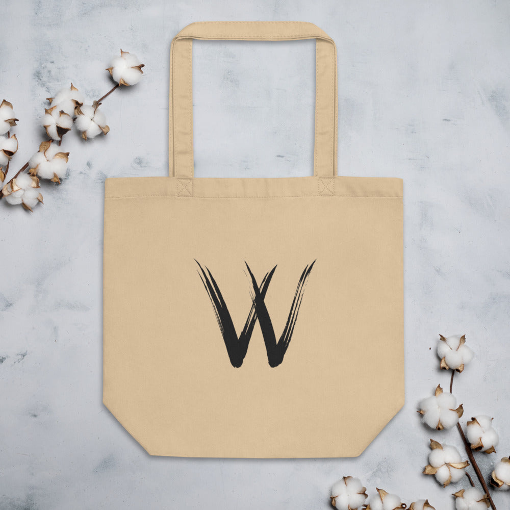 A minimalist sumi-e brush stroke design of the capital letter W printed on a tote bag. Flat lay, Bone colourway.