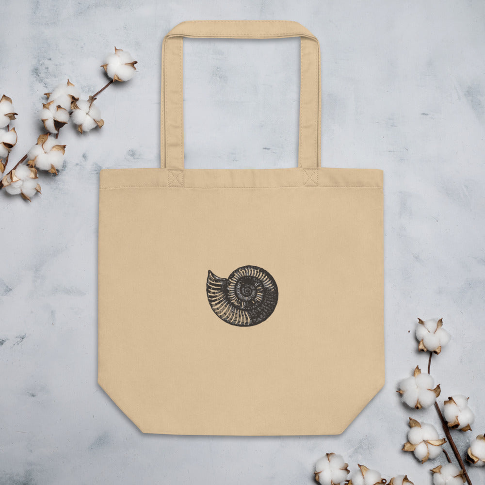 A canvas tote bag printed with a black line art illustration of a Scaphites nodosus ammonite shell. Flat lay, Bone colourway.