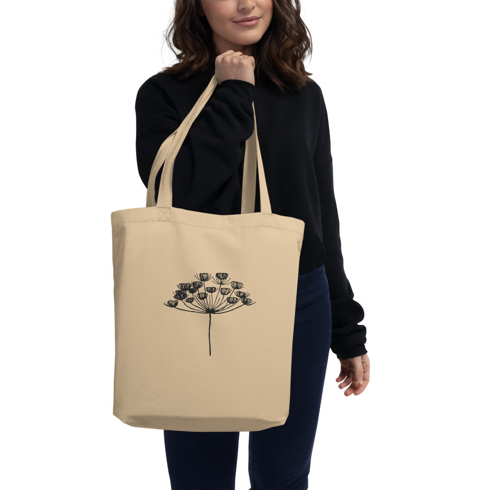 A fine-line botanical drawing of a dill seed umbel printed on a cotton tote bag. Carried over the shoulder, Bone colourway.