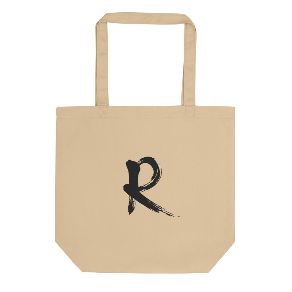 A minimalist sumi-e brush stroke design of the capital letter R printed on a tote bag. Shown on the Bone (Oyster) colorway.