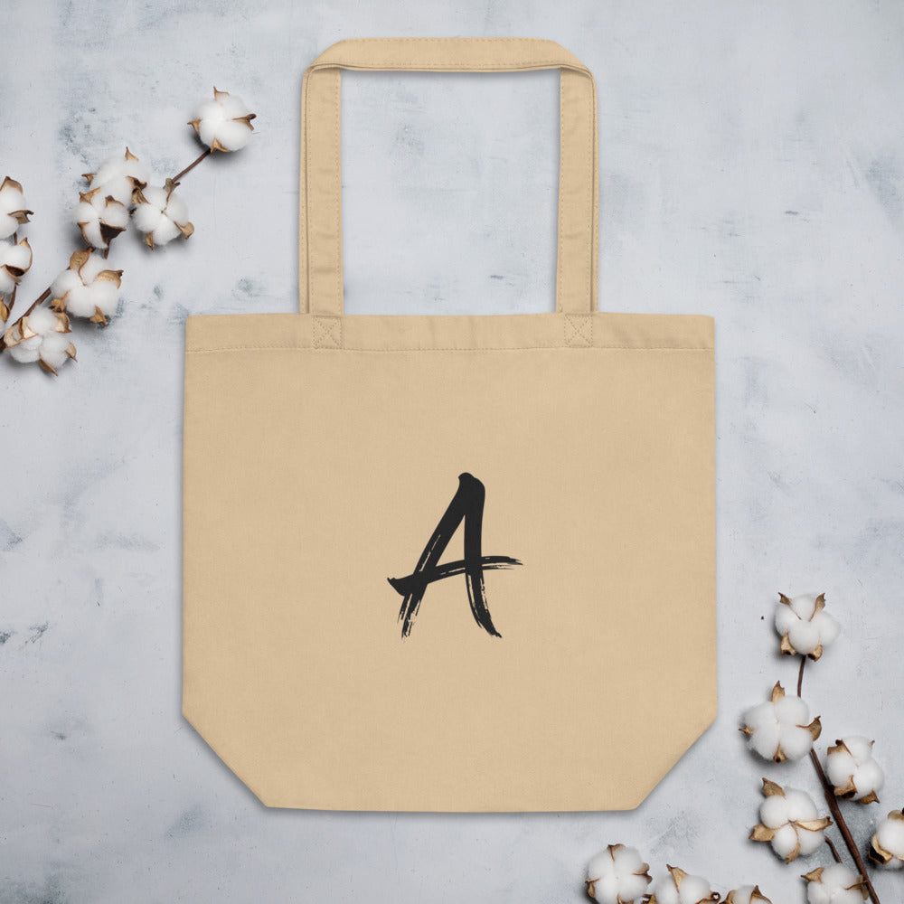 A minimalist sumi-e brush art design of the letter A printed on a fabric tote bag. Flat lay, Bone colourway.