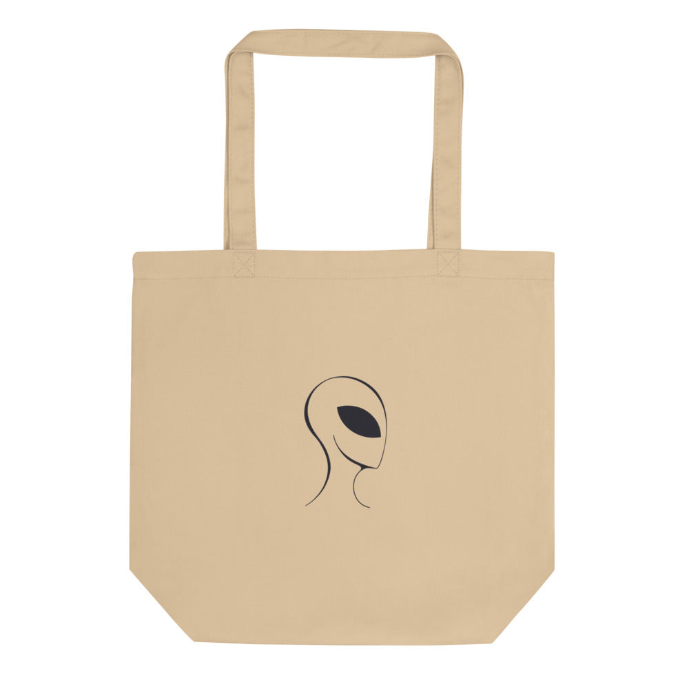 A clean line drawing of an alien visitor profile with a solid black almond-shaped eye printed on a tote bag. Shown on the Bone (Oyster) colorway.