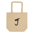 The letter J rendered in a single black sumi-e brush gesture, printed on a canvas tote bag. Shown on the Bone (Oyster) colorway.