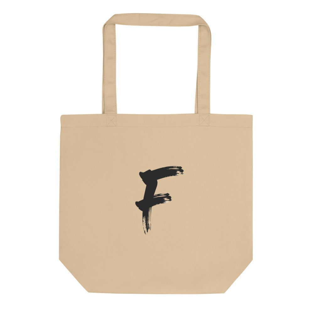 The capital letter F in bold black sumi-e brush strokes with dry-brush texture, printed on a tote bag. Shown on the Bone (Oyster) colorway.