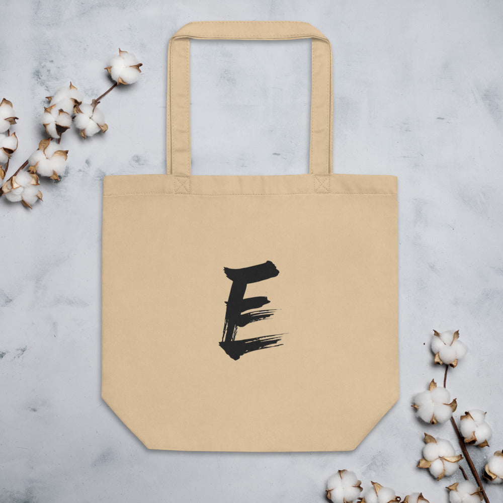A minimalist sumi-e style capital letter E printed in black ink on a tote bag. Flat lay, Bone colourway.
