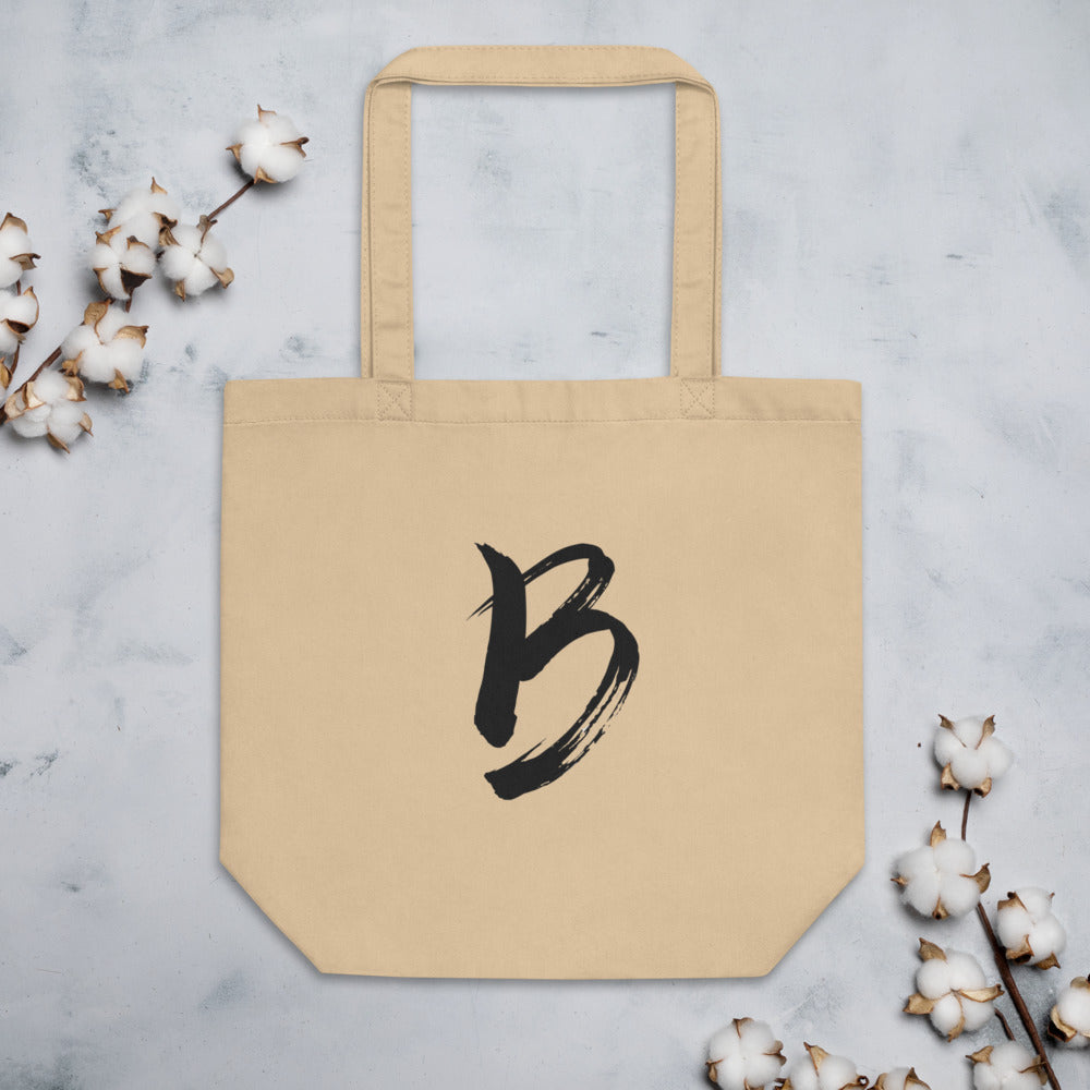 The capital letter B printed in minimalist sumi-e black ink on a tote bag. Flat lay, Bone colourway.
