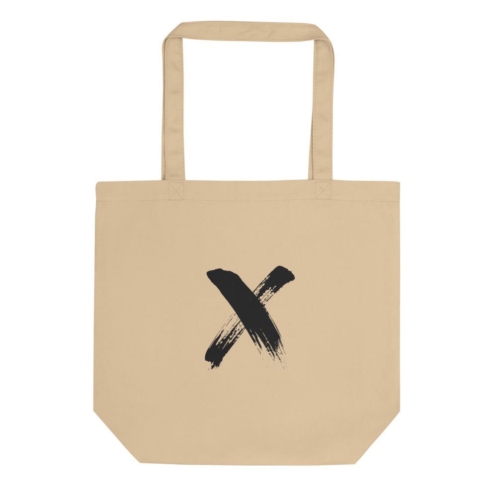 A black ink sumi-e calligraphy letter X printed on a canvas tote bag. Shown on the Bone (Oyster) colorway.