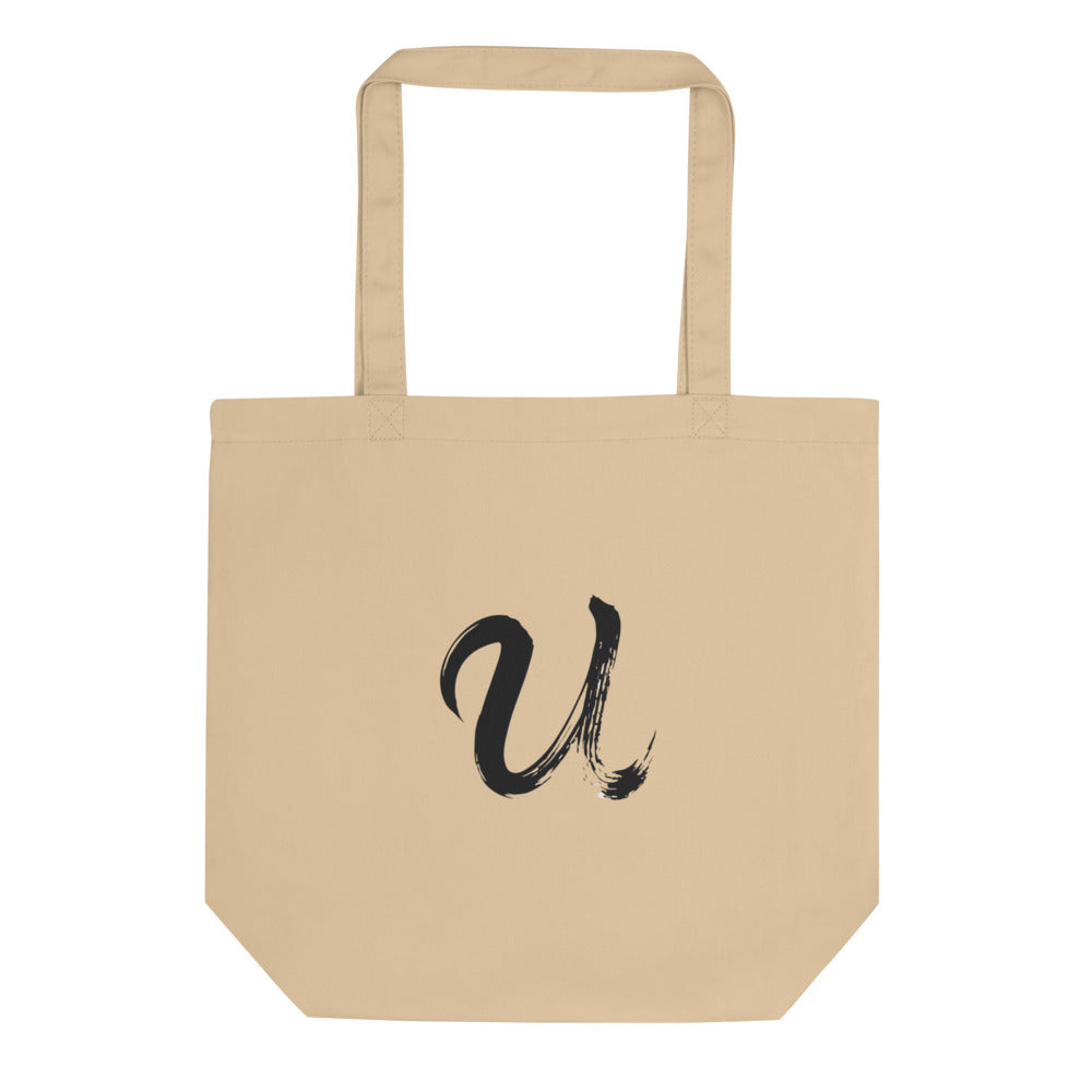 A black sumi-e ink brushstroke of the capital letter U printed on a tote bag. Shown on the Bone (Oyster) colorway.