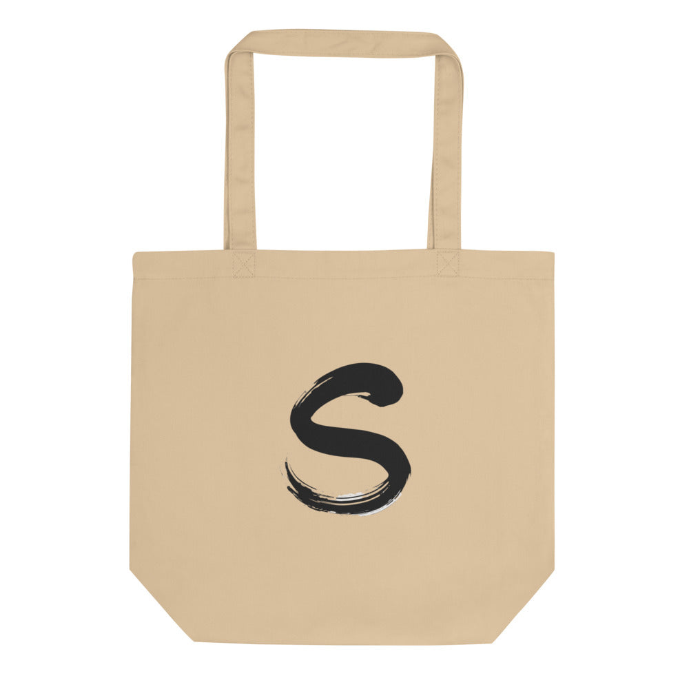 The letter S rendered in a single serpentine sumi-e brush stroke printed on a tote bag. Shown on the Bone (Oyster) colorway.