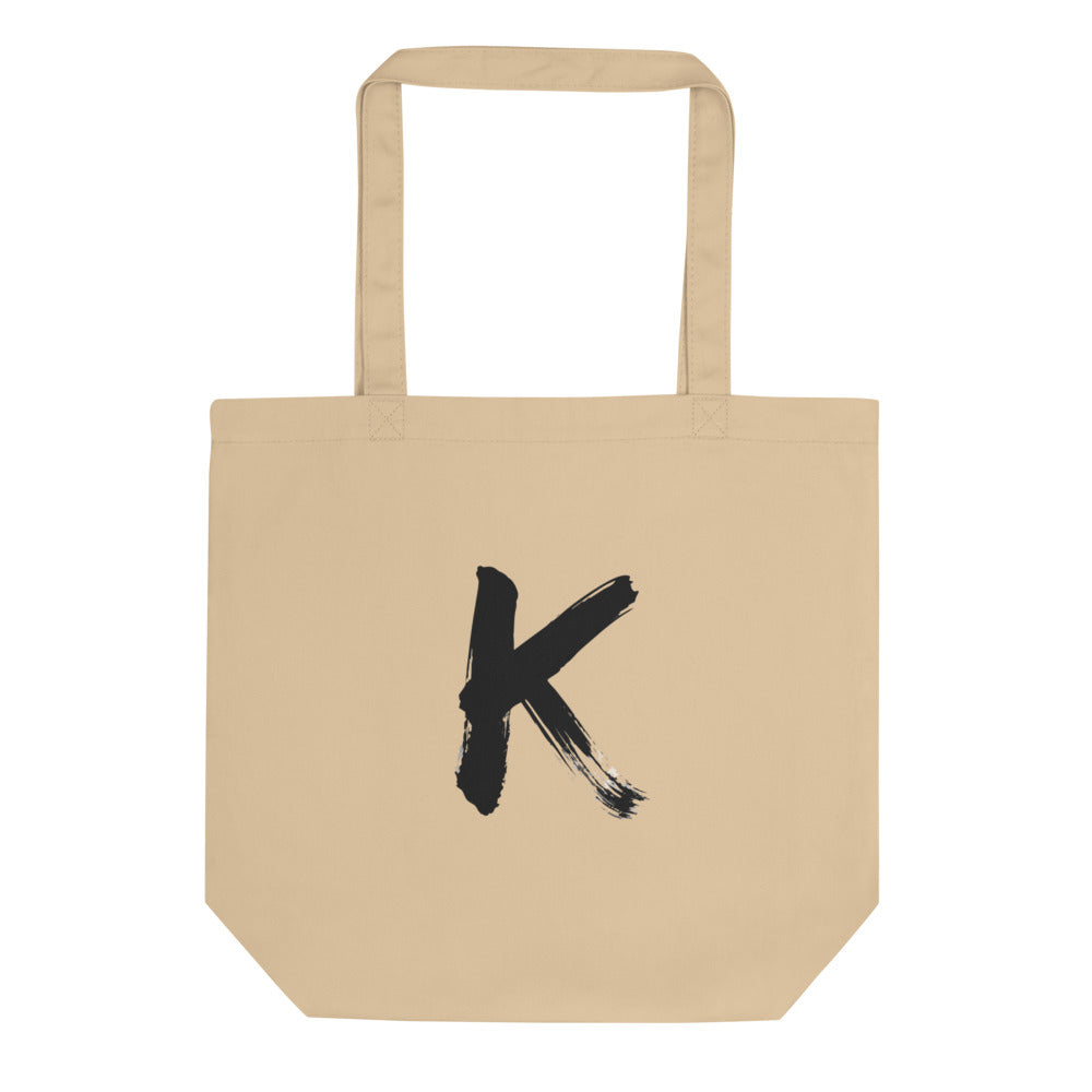 Sumi-e ink brush painting of the capital letter K printed on a canvas tote bag. Shown on the Bone (Oyster) colorway.