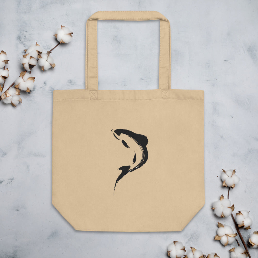 A minimalist sumi-e brushstroke of a rising trout back and tail printed on a tote bag. Flat lay, Bone colourway.