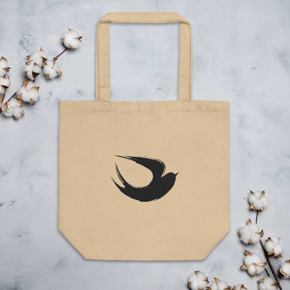 A minimalist sumi-e ink brush painting of a flying swallow on a tote bag. Flat lay, Bone colourway.