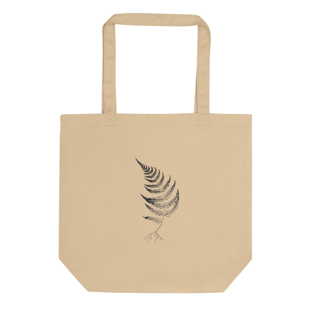 A wood fern engraving featuring detailed root structures and arched fronds, printed on a tote bag. Shown on the Bone (Oyster) colorway.