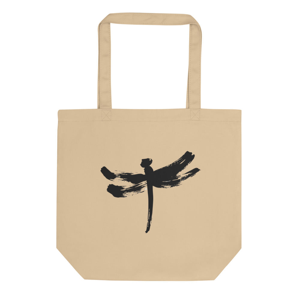 A minimalist dragonfly sumi-e ink design printed on a canvas tote bag. Shown on the Bone (Oyster) colorway.