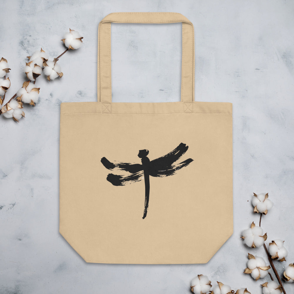 A minimalist dragonfly sumi-e ink design printed on a canvas tote bag. Flat lay, Bone colourway.