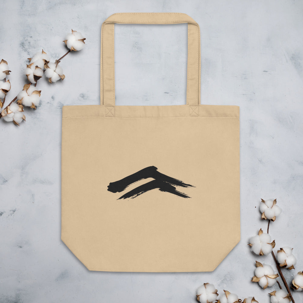 A minimalist sumi-e painting of two dry-brush mountain ridges printed on a tote bag. Flat lay, Bone colourway.