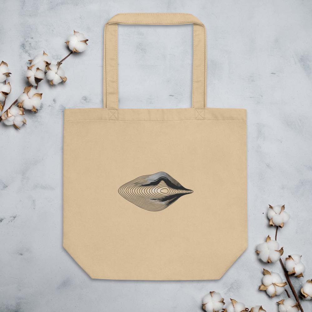 An engraving-style topographic contour design forming an asymmetric eye printed on a tote bag. Flat lay, Bone colourway.