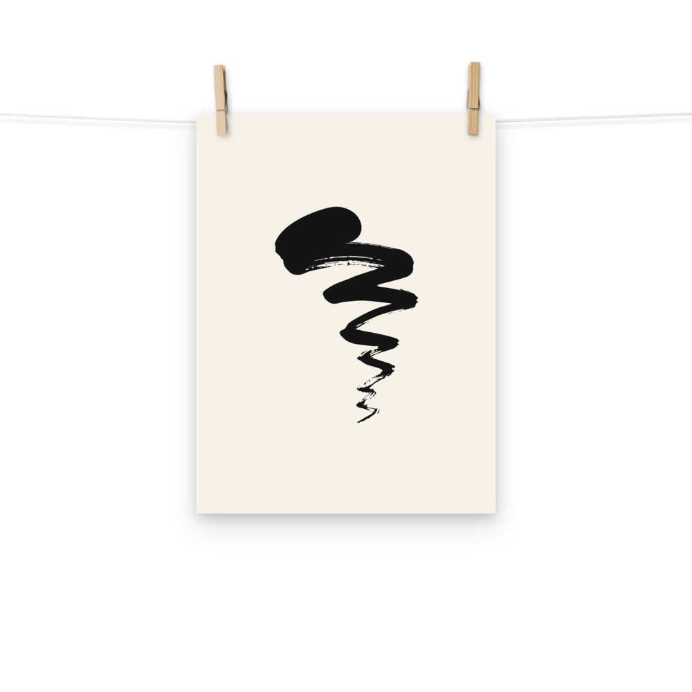 A black sumi-e ink painting of a swimming tadpole with a thick head and dry-brush tail printed on a paper art print. Hung with wooden pegs, 12″×16″ size.