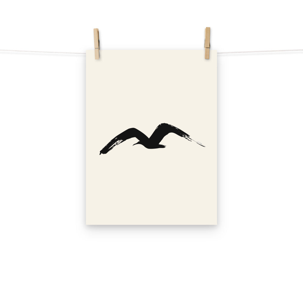 A single M-shaped sumi-e brush stroke representing a gliding gull, printed on a fine art print. Hung with wooden pegs, 12″×16″ size.