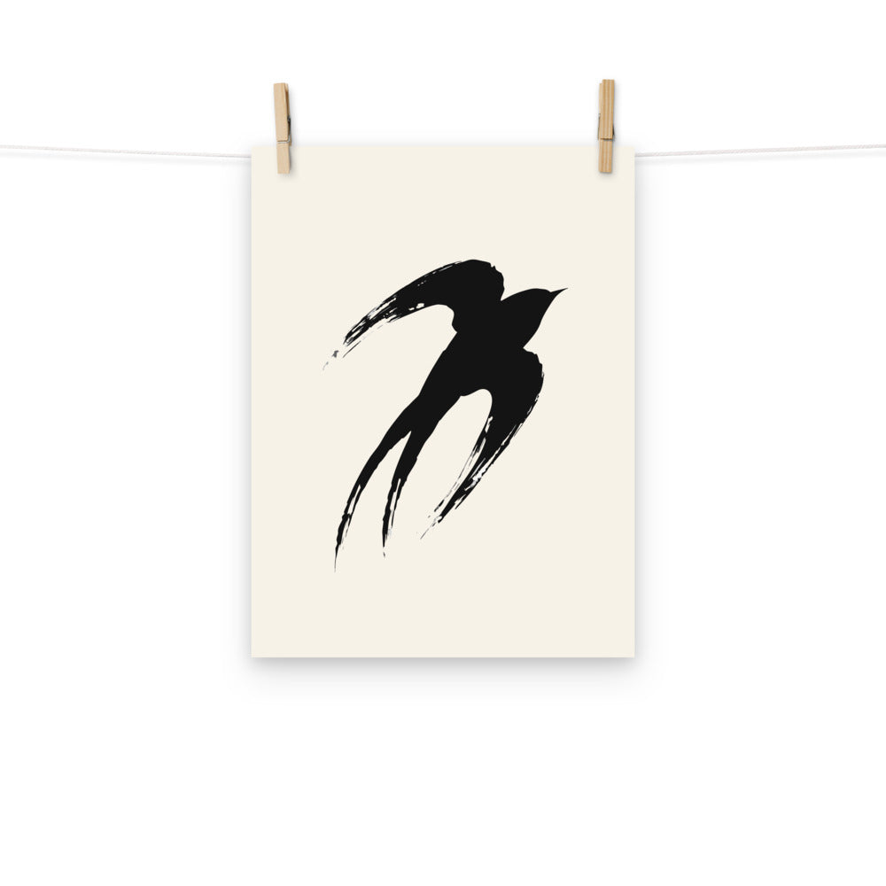 A minimalist sumi-e ink painting of an ascending swallow printed on an art print. Hung with wooden pegs, 12″×16″ size.