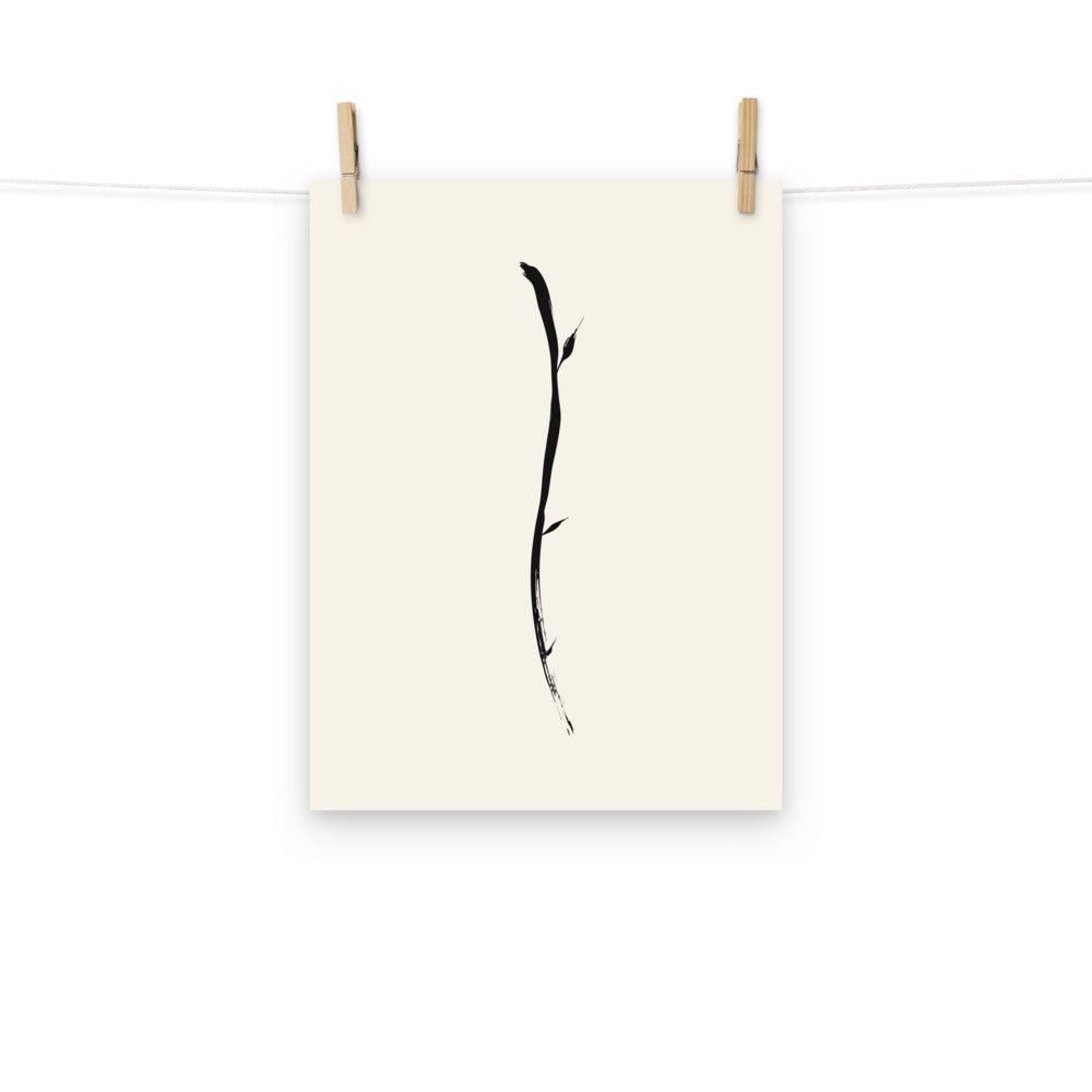 Minimalist sumi-e ink design of a single drooping willow twig printed on an art print. Hung with wooden pegs, 12″×16″ size.