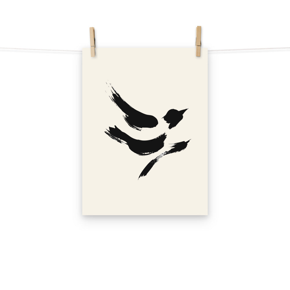 The minimal sumi-e design of a diving sparrow printed on a white art print. Hung with wooden pegs, 12″×16″ size.