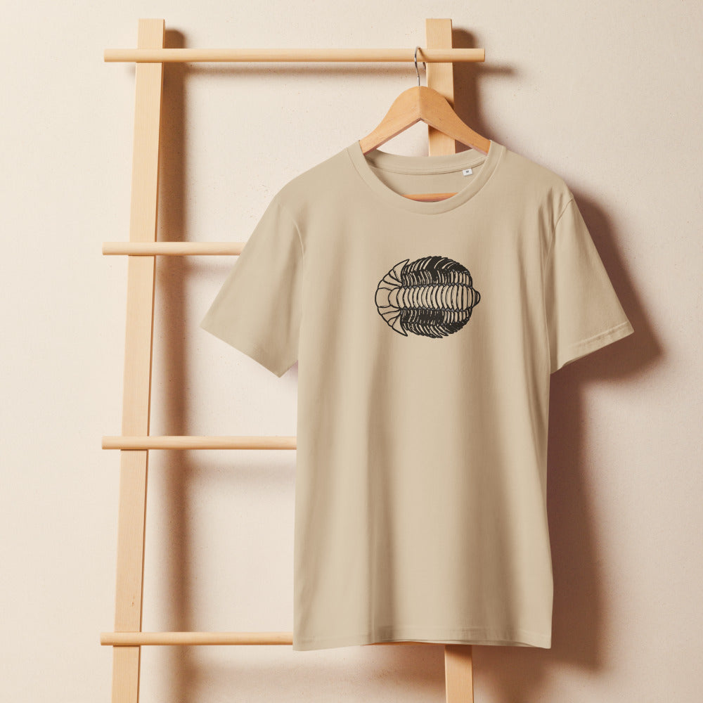A detailed lithograph-style scientific illustration of a Calymene blumenbachii trilobite printed on a t-shirt. On a wooden hanger, Clay colourway.