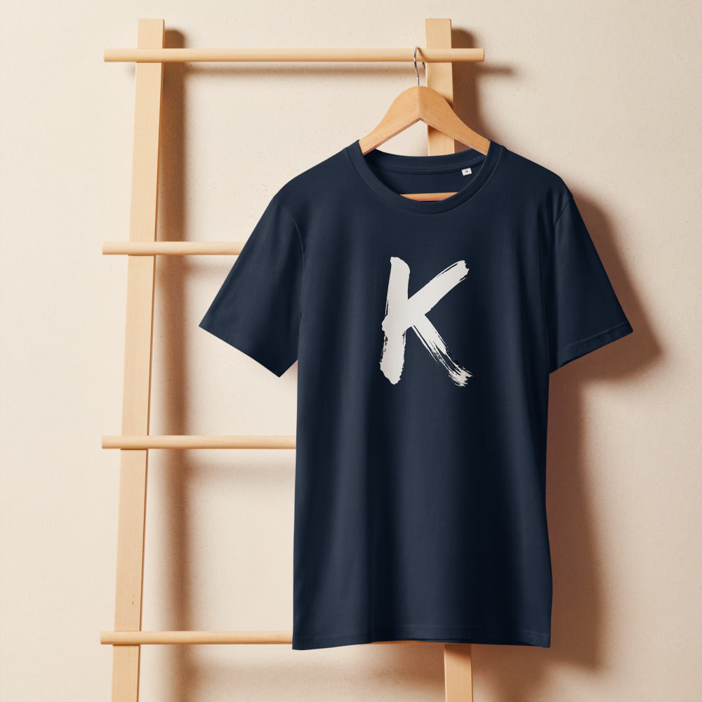 Sumi-e ink brush painting of the capital letter K printed on a t-shirt. On a wooden hanger, Ink colourway.