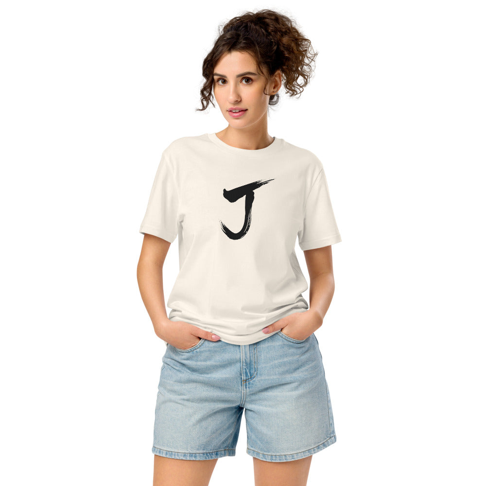 The letter J rendered in a single black sumi-e brush gesture, printed on a classic t-shirt. Worn by a woman, Bone colourway.