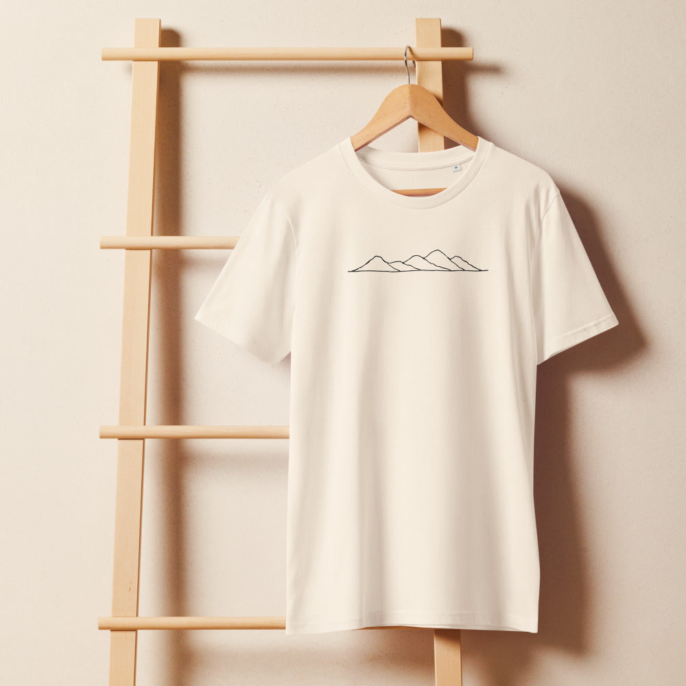 A minimalist topographic line art print showing five rolling hill peaks on a cotton t-shirt. On a wooden hanger, Bone colourway.
