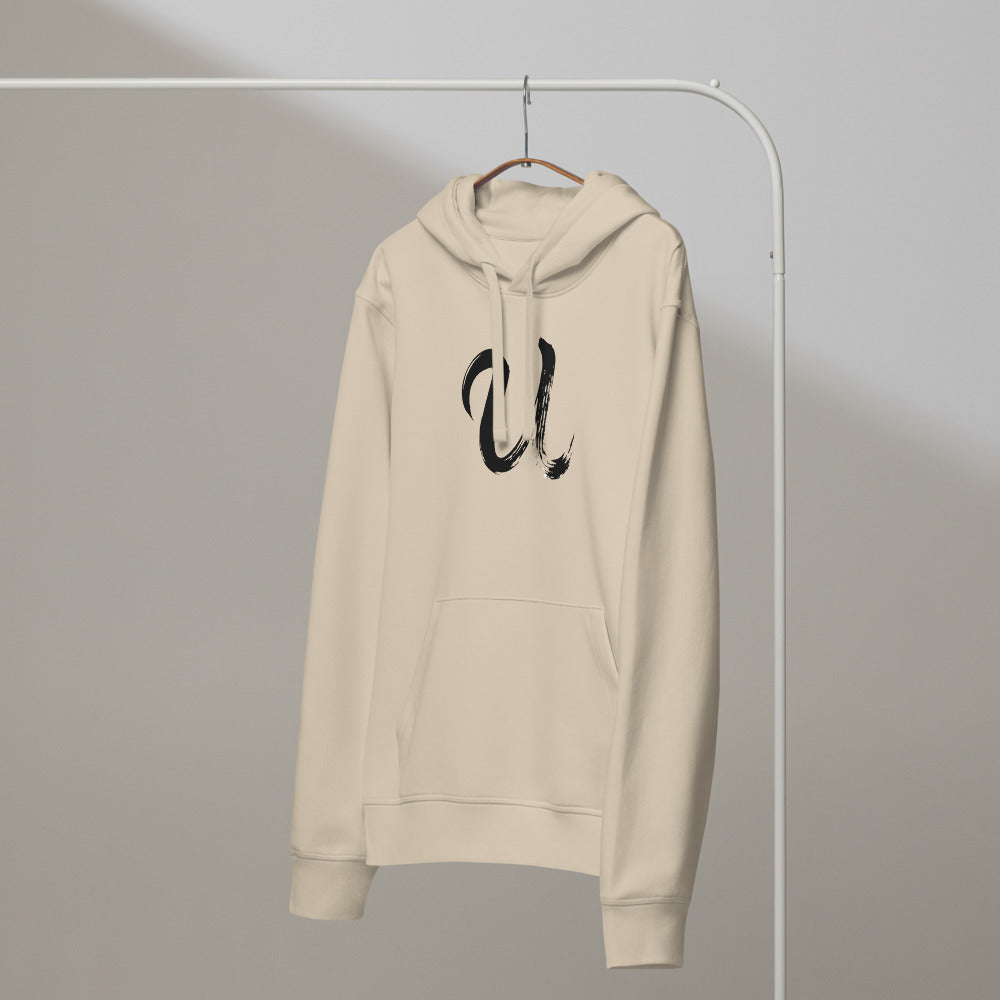 A minimalist black sumi-e ink brushstroke of the capital letter U printed on a hoodie. On a hanger, Clay colourway.