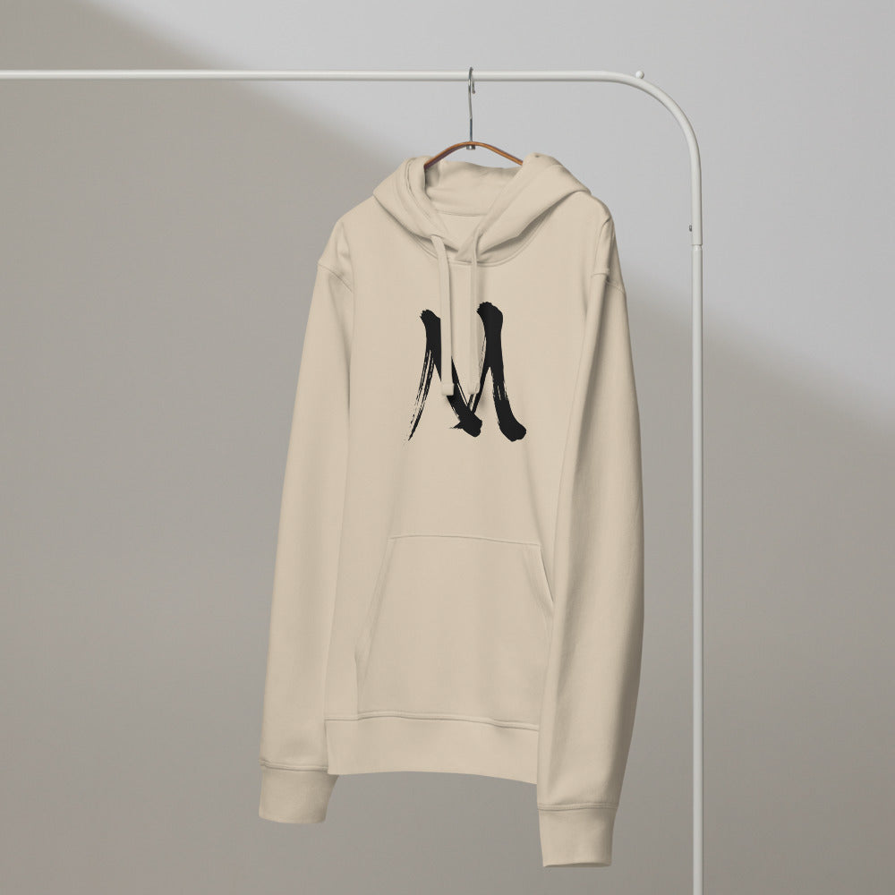 The letter M in black sumi-e brush stroke style printed on a minimalist hoodie. On a hanger, Clay colourway.