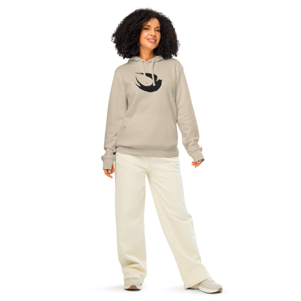 A minimalist sumi-e ink brush painting of a flying swallow on a hoodie. Worn by a woman, Clay colourway.
