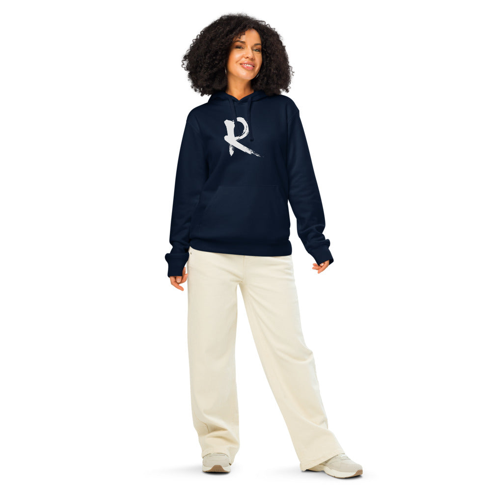 A minimalist sumi-e brush stroke design of the capital letter R printed on a hoodie. Worn by a woman, Ink colourway.