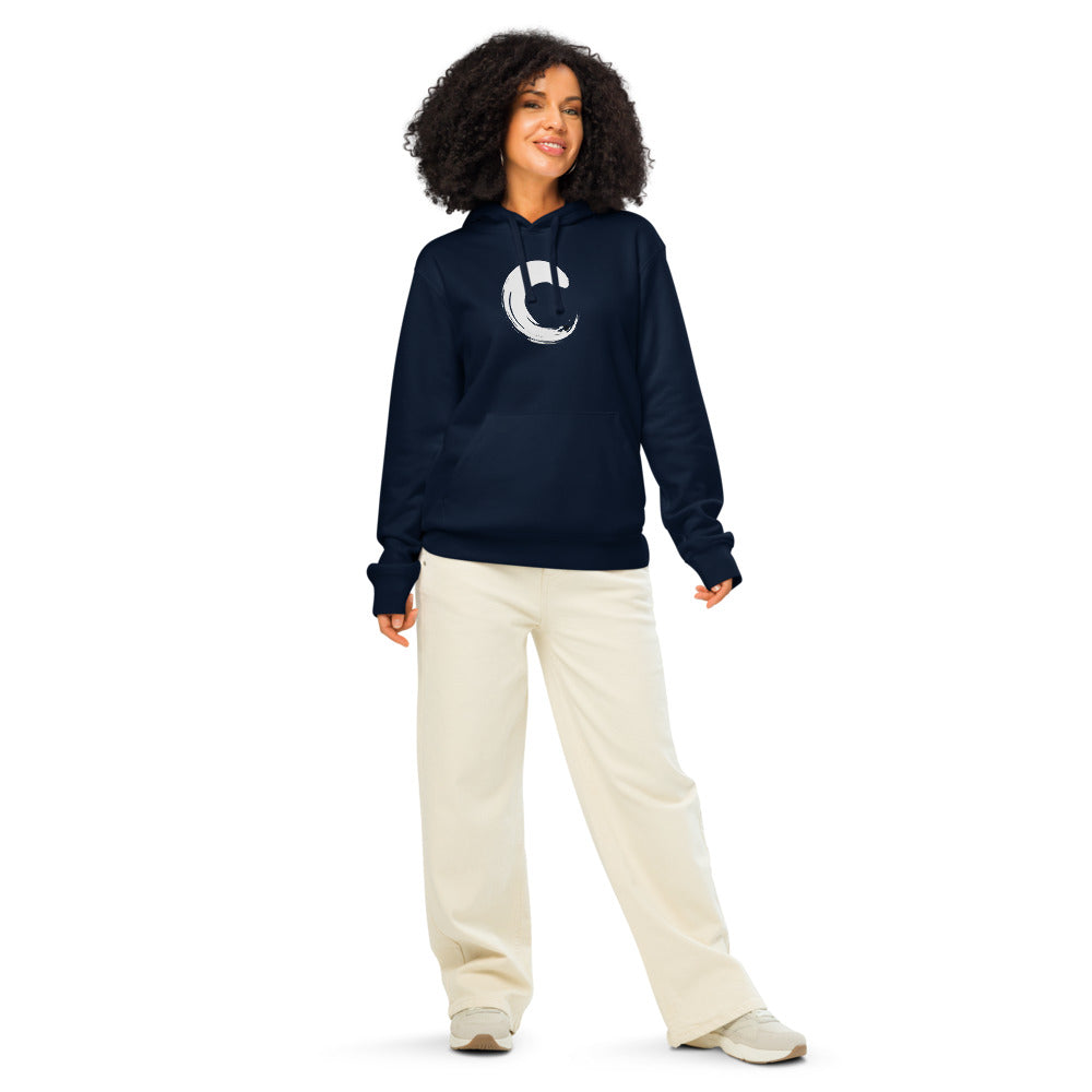 The capital letter C printed as a black sumi-e brush gesture on a hoodie. Worn by a woman, Ink colourway.