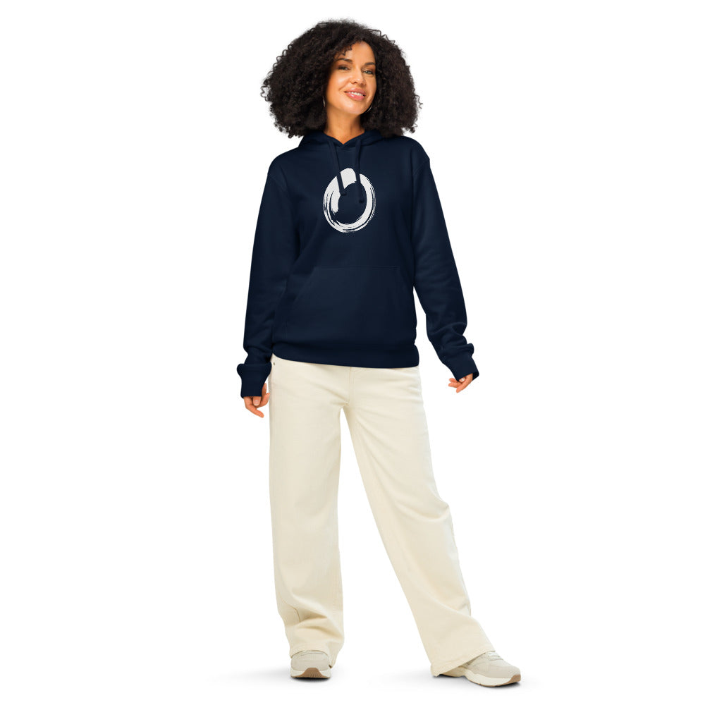 A single black sumi-e brushstroke forming an unclosed letter O on a hoodie. Worn by a woman, Ink colourway.