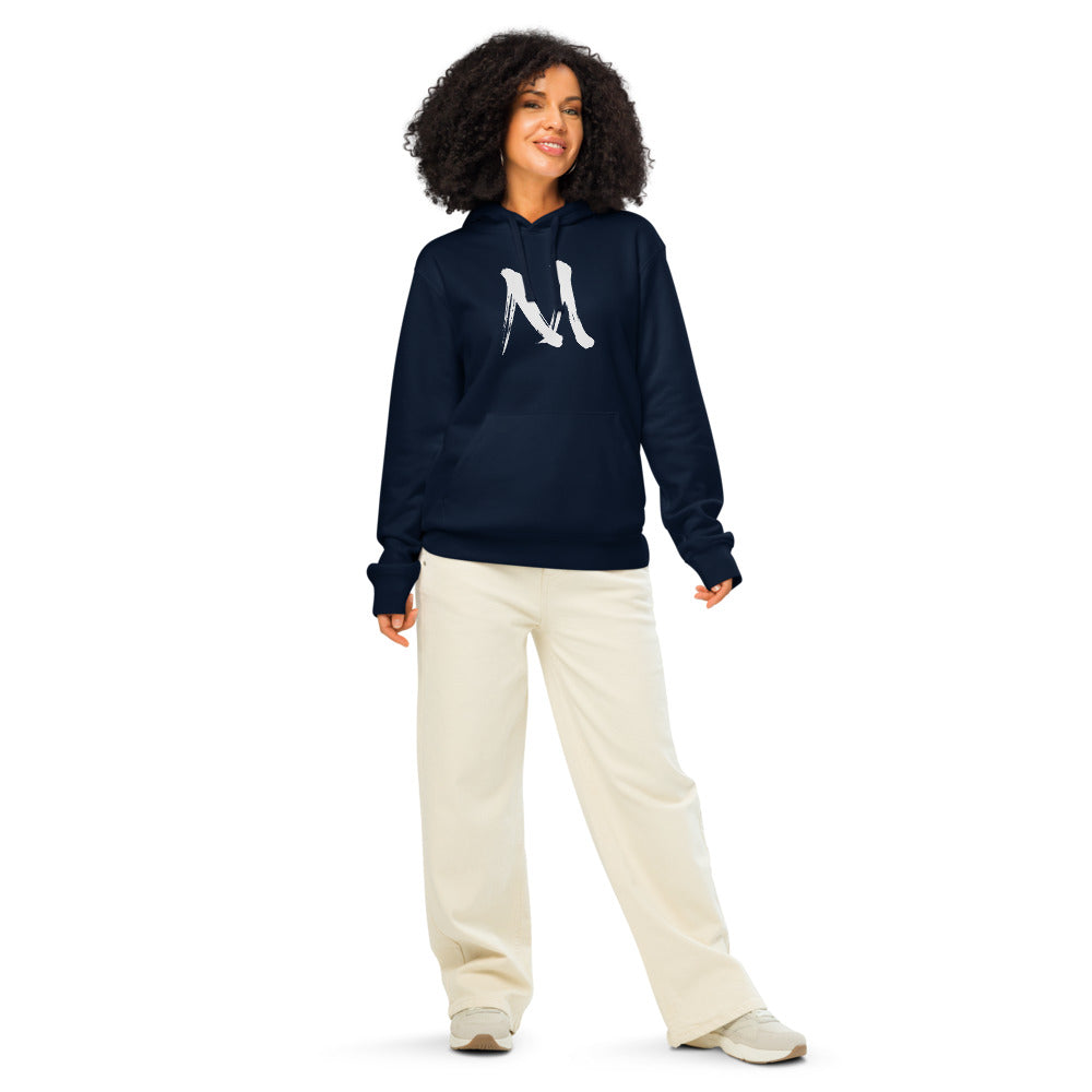 The letter M in black sumi-e brush stroke style printed on a minimalist hoodie. Worn by a woman, Ink colourway.