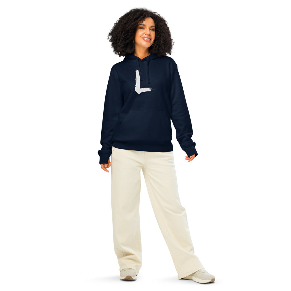 A minimalist black ink sumi-e stroke forming the letter L, printed on a classic hoodie. Worn by a woman, Ink colourway.